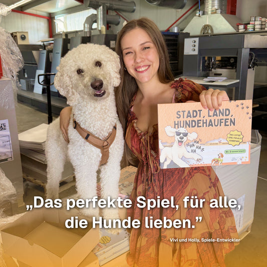 Vivi und Holly halten den Spielblock Stadt, Land, Hundehaufen in der Druckerei – das Spiel für alle, die Hunde lieben